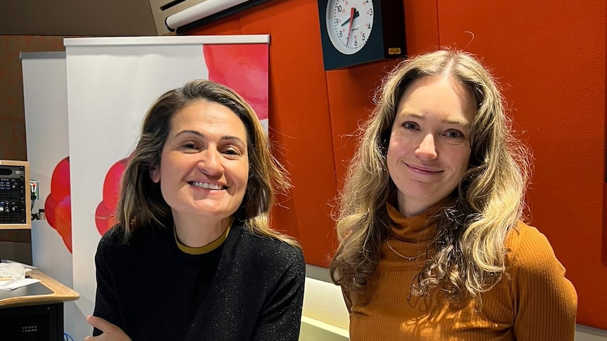 two women stand next to each other in studio, both are smiling 