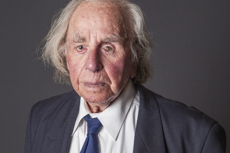 A studio portrait of an old man wearing a suit and military medals.