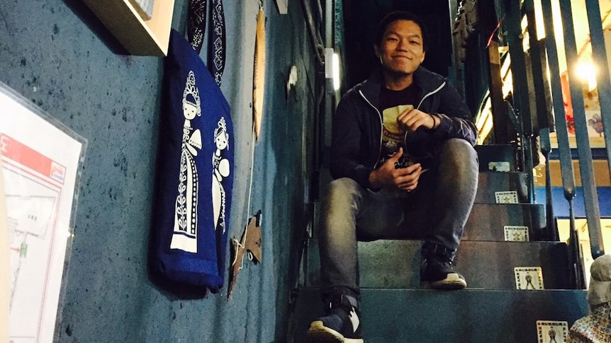 Lee Sang-jun sitting on some stairs and smiling