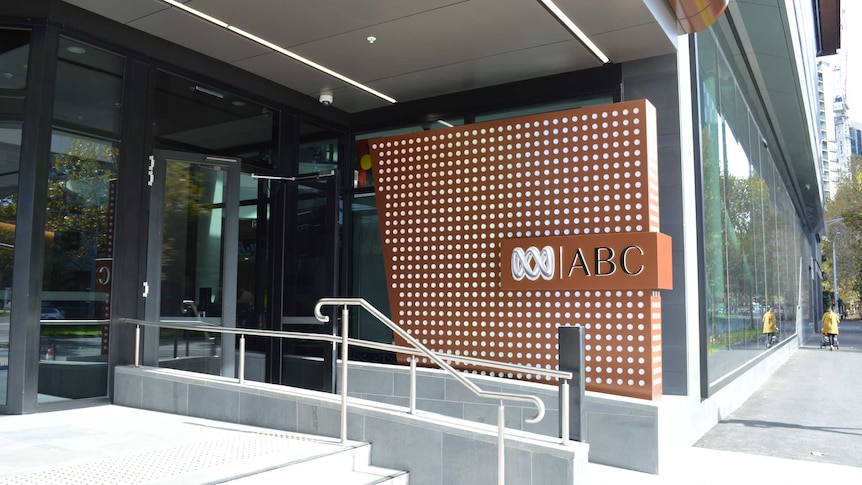 A large brown sign displays an ABC logo outside the entry to a building.