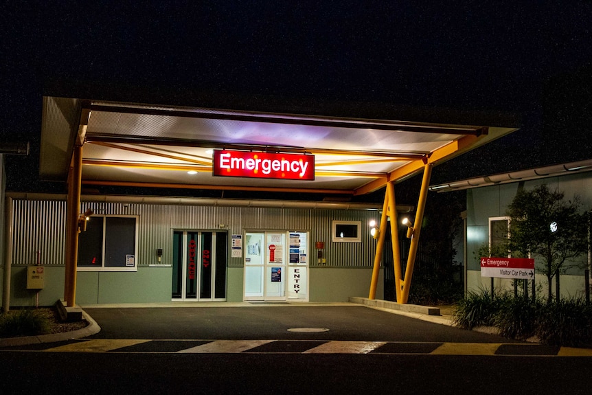 The emergency sign at Narrabri hospital glowing in the night over the entrance.