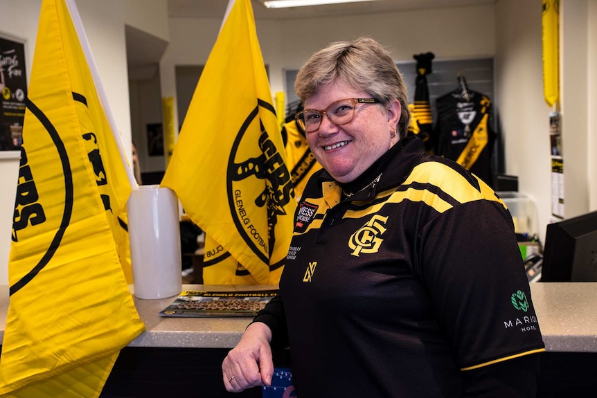 A woman stands near black and yellow flags