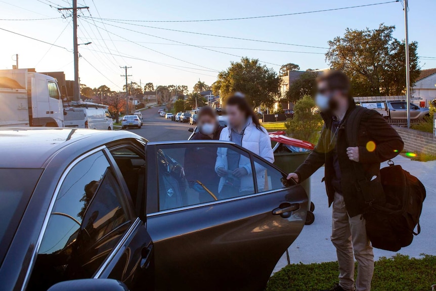 a woman being led into a black car by masked law enforcement