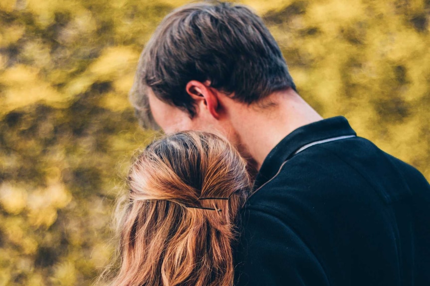 A man rests his head on a woman's head.