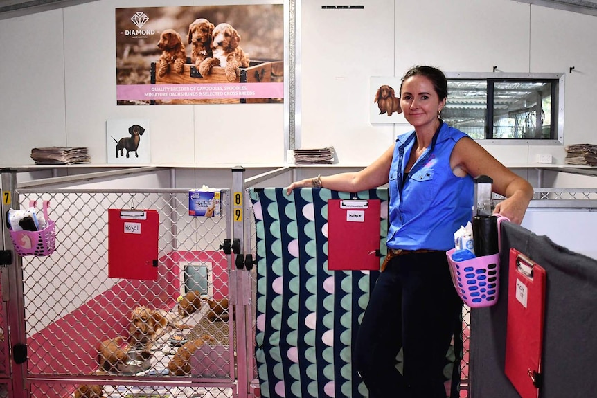 A woman stands outside a caged puppy nursery