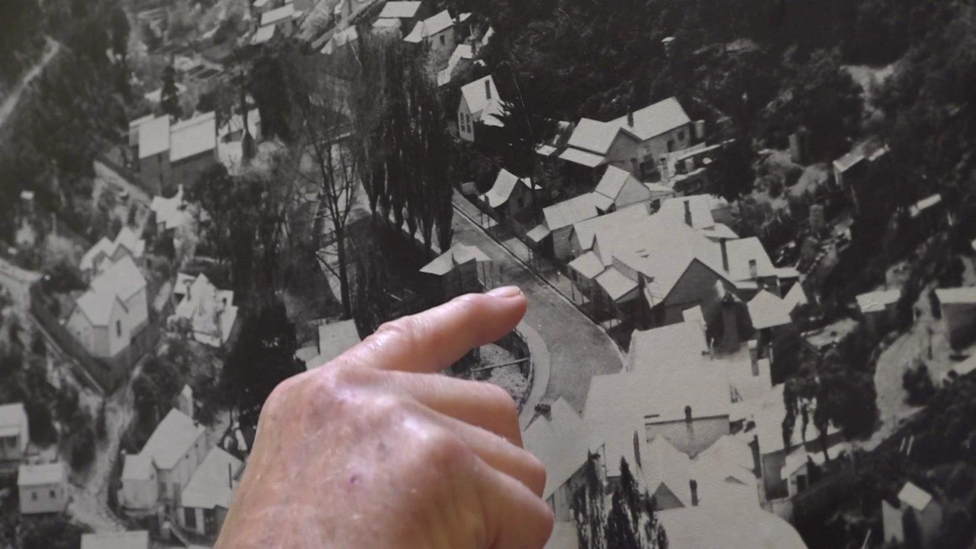 A finger points at a black and white photo of a street