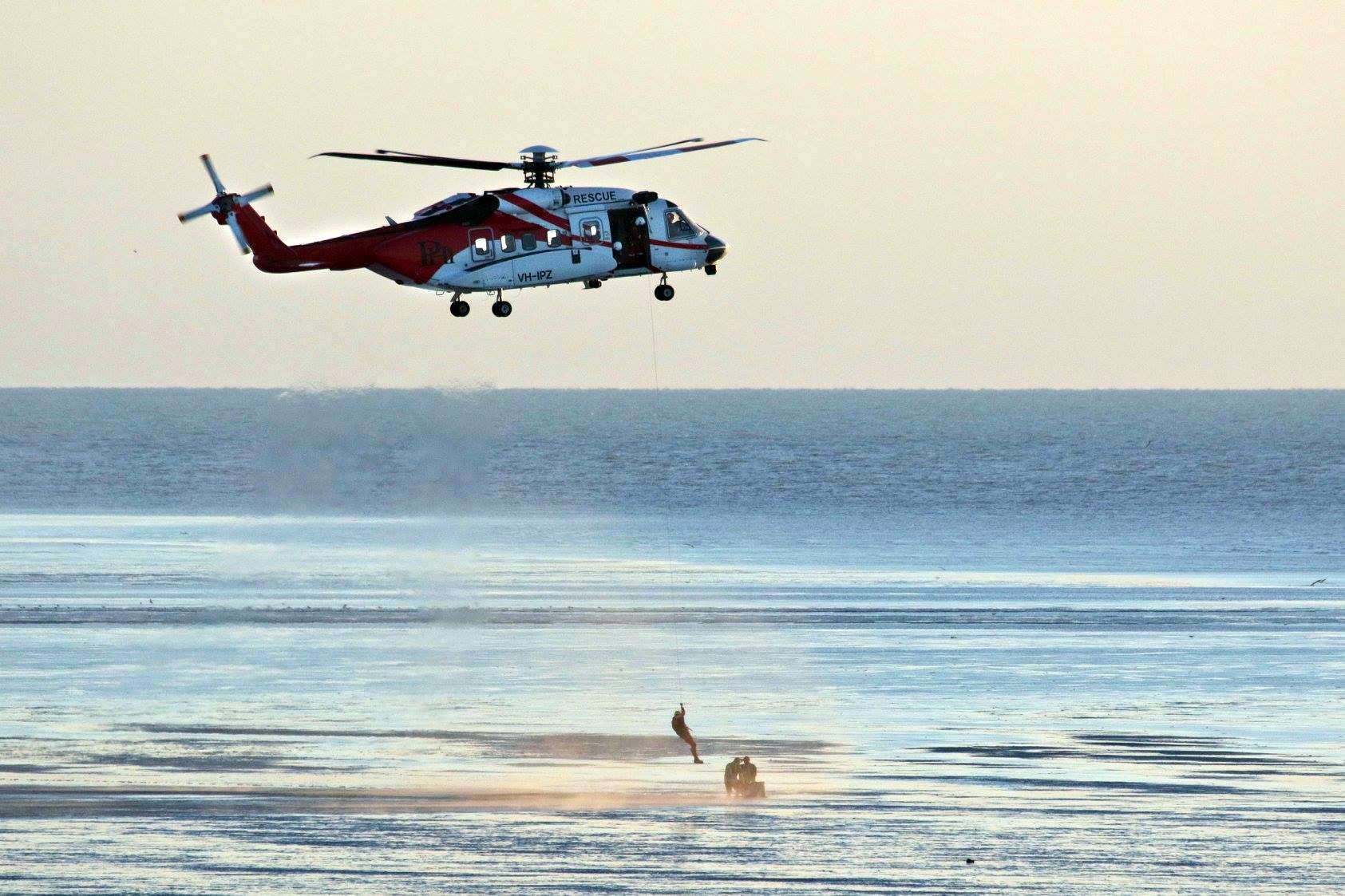 A helicopter is used to winch two men to safety.