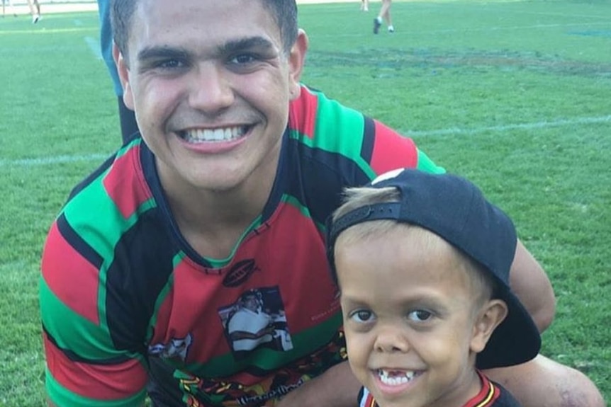 NRL star Latrell Mitchell smiles for the camera with Quaden Bayles, a child wearing a number 3 Philadelphia 76ers jersey.