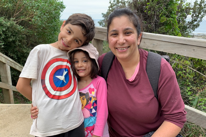 a mother and her two young children smile.