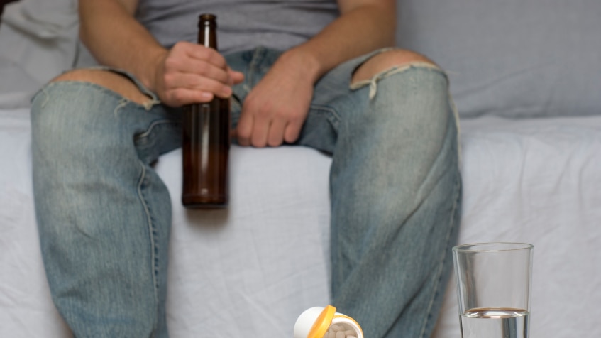 Young person drinking and taking pills