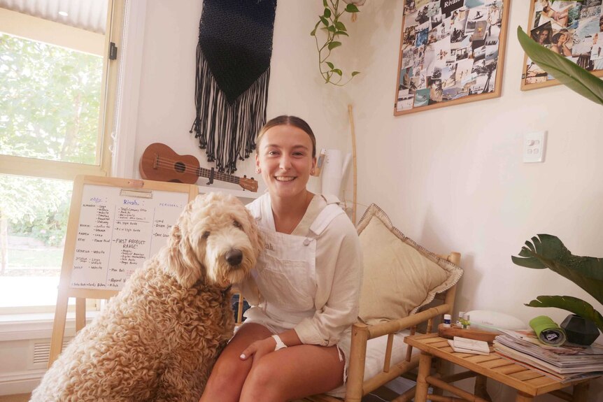 Ebony Forsyth sitting on a chair in her home office with her dog at her side.