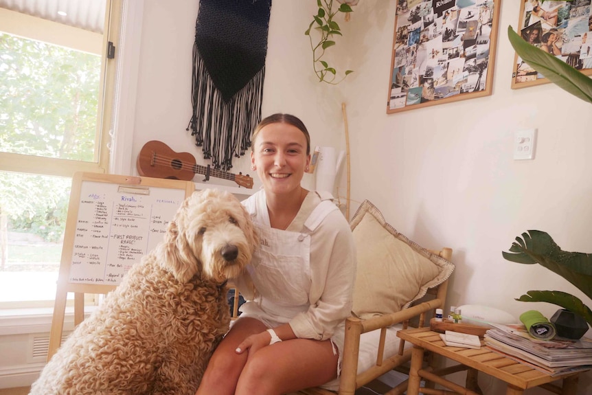 Ebony Forsyth sitting on a chair in her home office with her dog at her side.