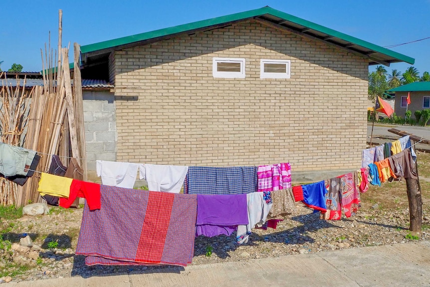 A line of laundry strung across lines in front of brick homes