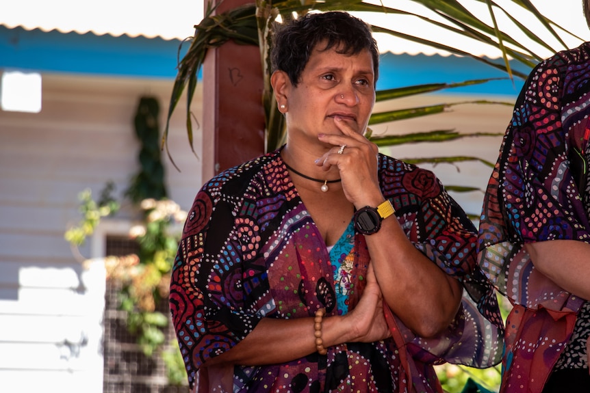 Yvette Roe looks seriously with her hand on her chin. She is wearing bright colours.