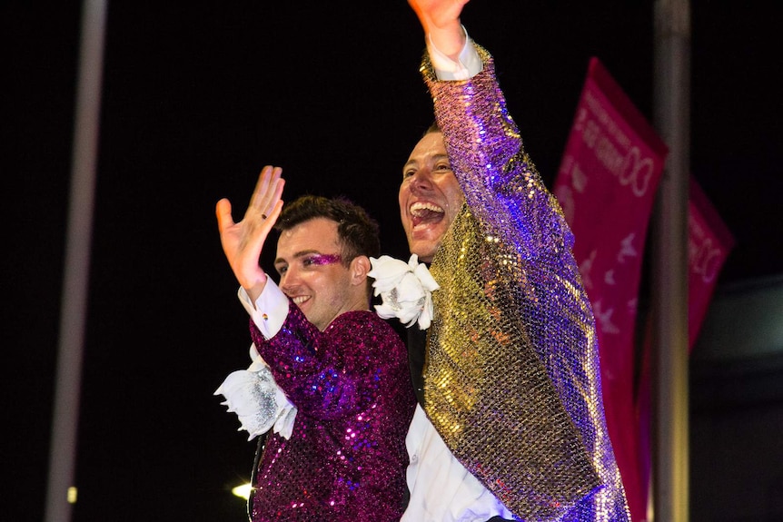Two men wave during the Sydney Mardis Gras.