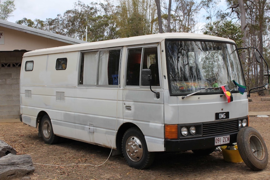 A large white van with an Aboriginal and a Torres Strait Islander flag on the windscreens and the numberplate OMG.