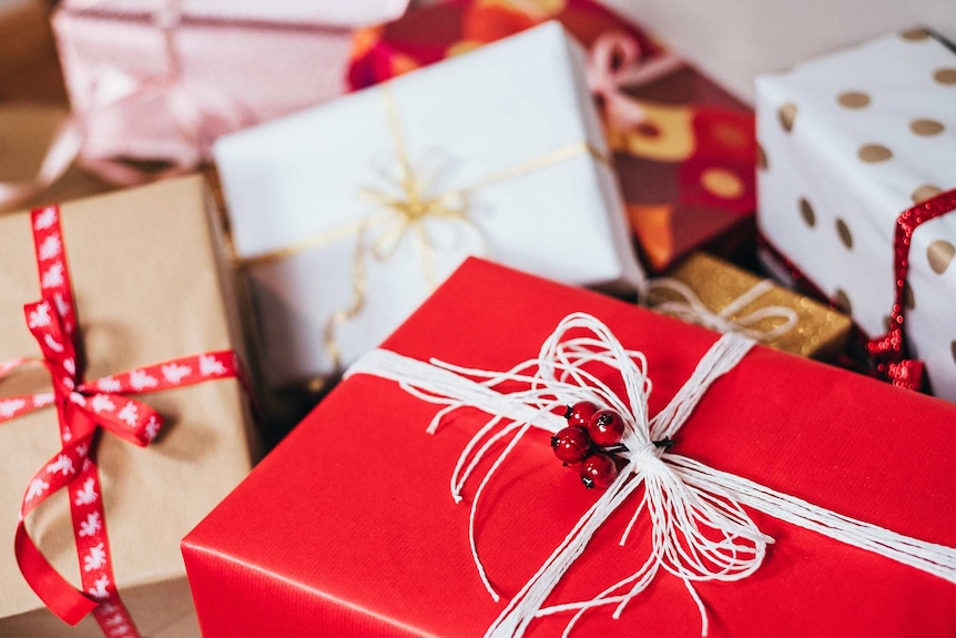 A bunch of wrapped Christmas presents in a pile.