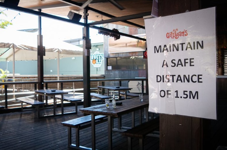 A sign urges non-existent patrons to sit at least 1.5m apart. A couple of empty glasses sit on a table.