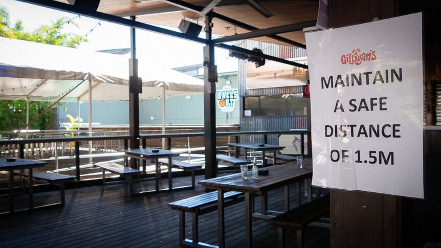 A sign urges non-existent patrons to sit at least 1.5m apart. A couple of empty glasses sit on a table.