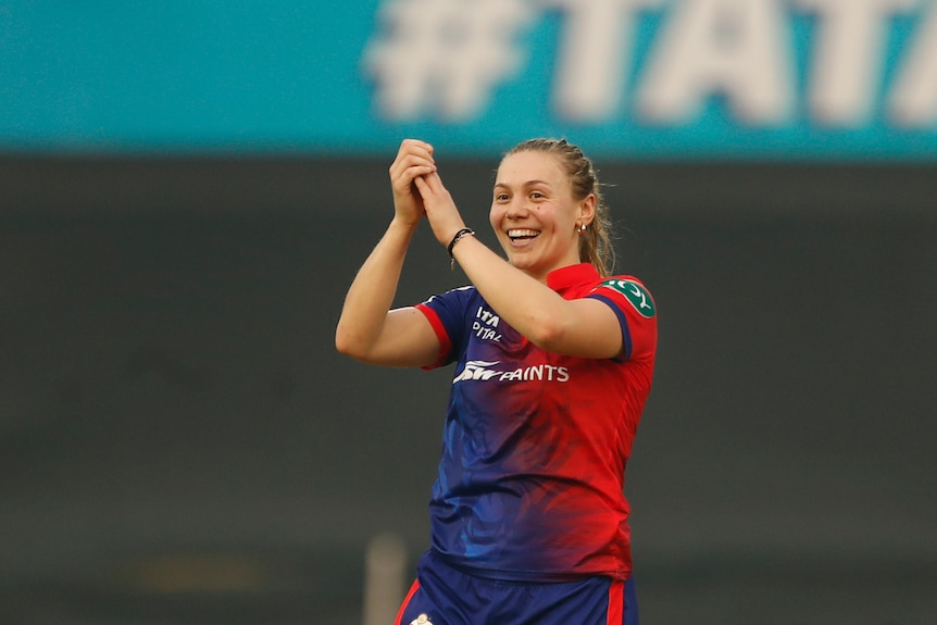 Tara Norris of Delhi Capitals claps in the air and smiles after taking a wicket.