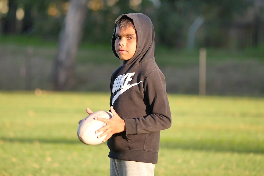 A child holds a rugby ball.