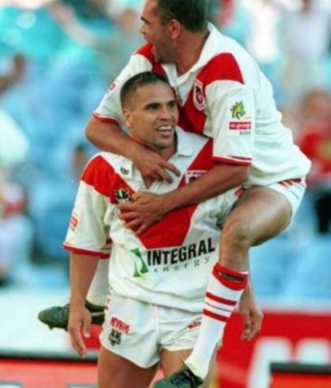 One rugby league player jumping on another in celebration during a match  