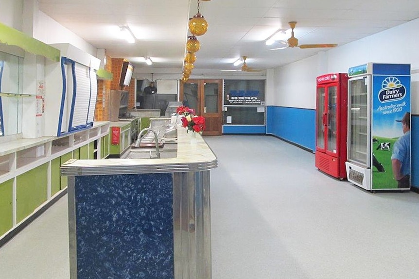 Interior of empty cafe fitted with empty fridges, and long sink