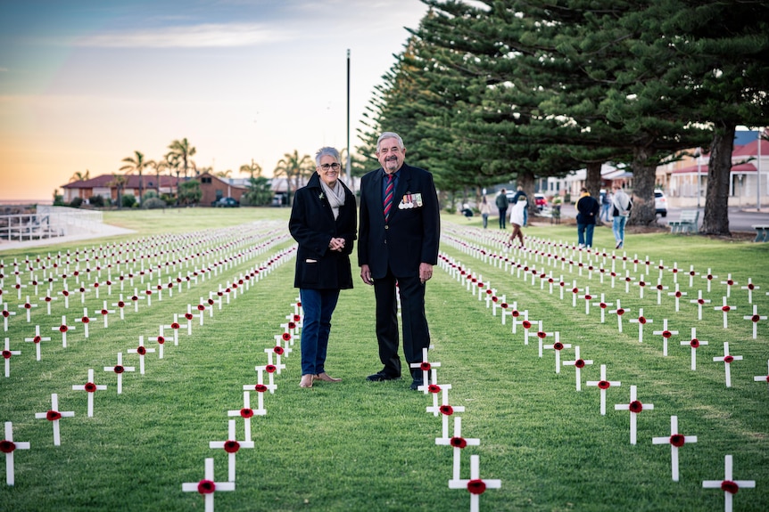 woman and man standing amid field of crosses
