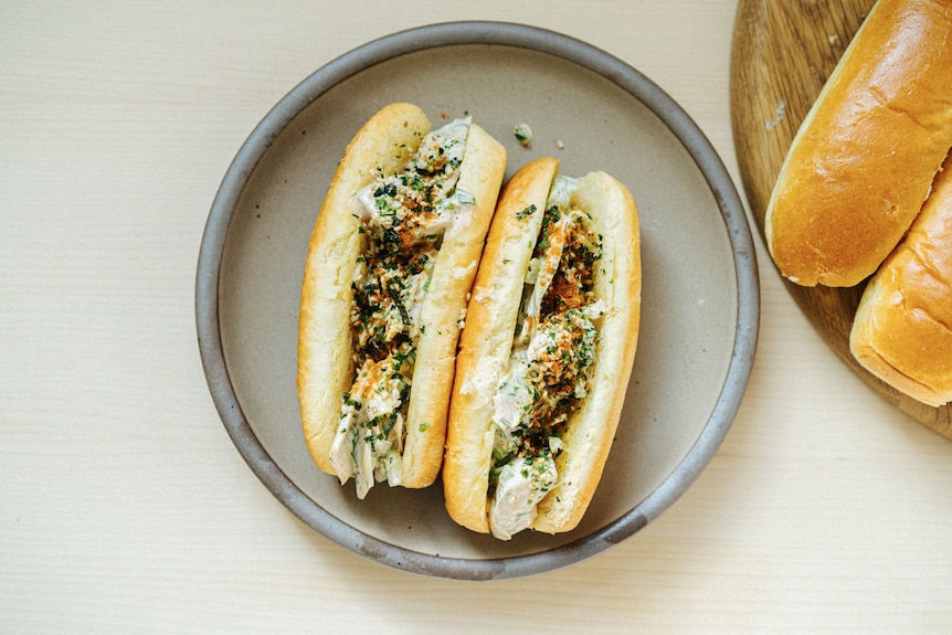 Two long brioche rolls with artichoke filling on a plate, a vegetarian take on the lobster roll.