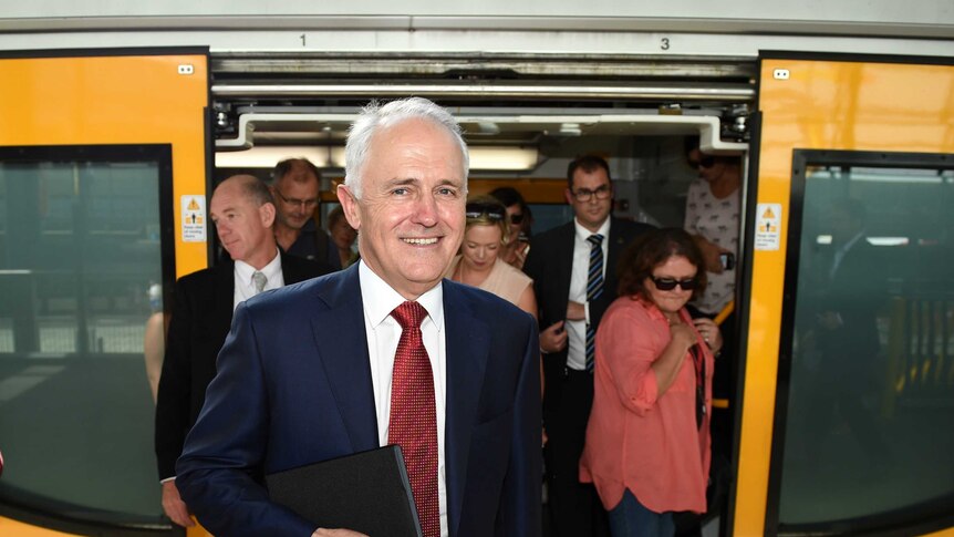 A smiling Malcolm Turnbull alights from a Sydney train