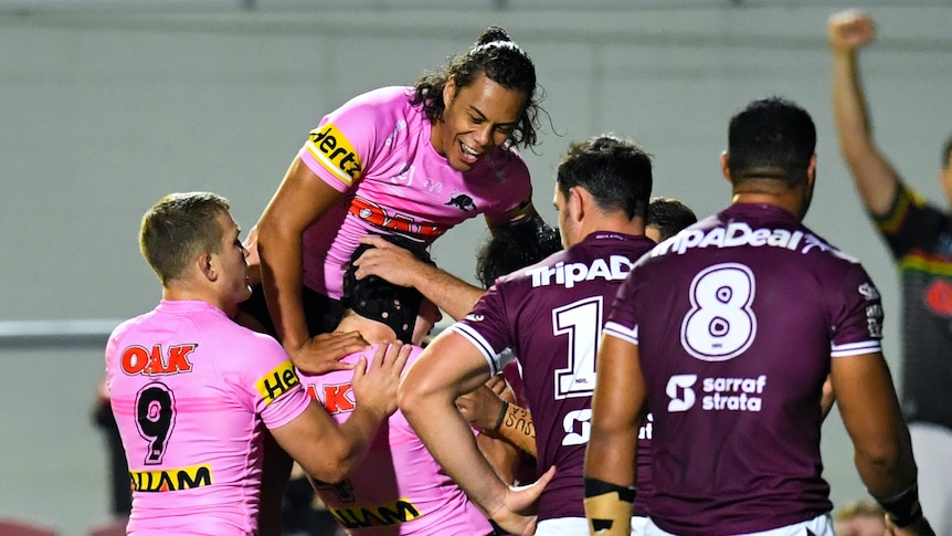 Rugby League players jumping on teammate in celebration after scoring a try.