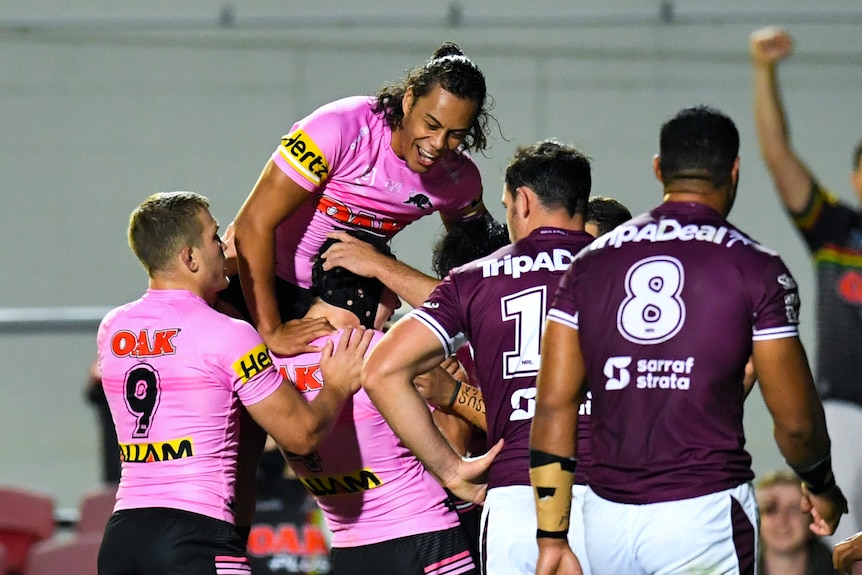 Rugby League players jumping on teammate in celebration after scoring a try.