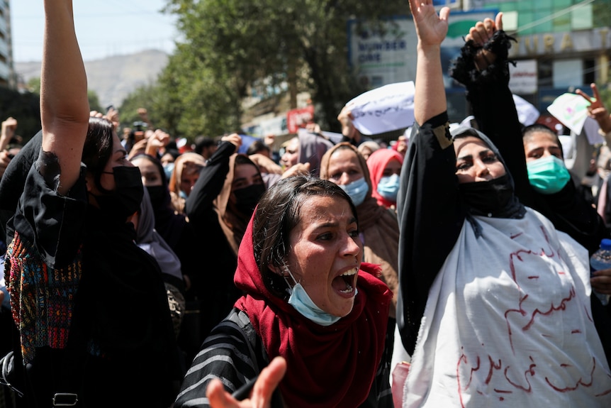 A shouting woman is seen at the front of a crowd of protesters