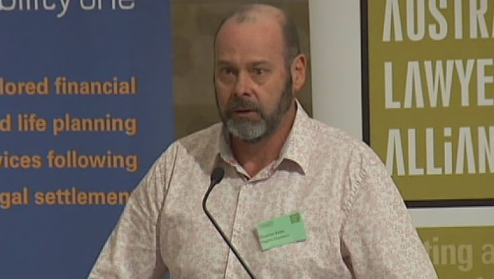 TV still of Brisbane barrister Stephen Keim speaking at a legal conference on the Gold Coast