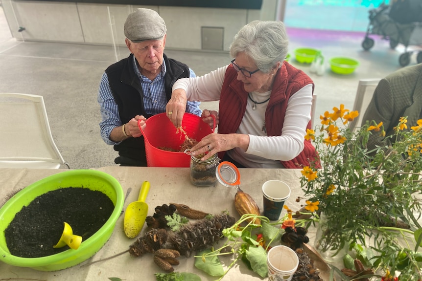 Mike and Anne Jobbins playing with moss as they make their take-home terrarium.