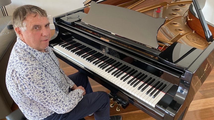 Man sitting at grand piano looking at camera