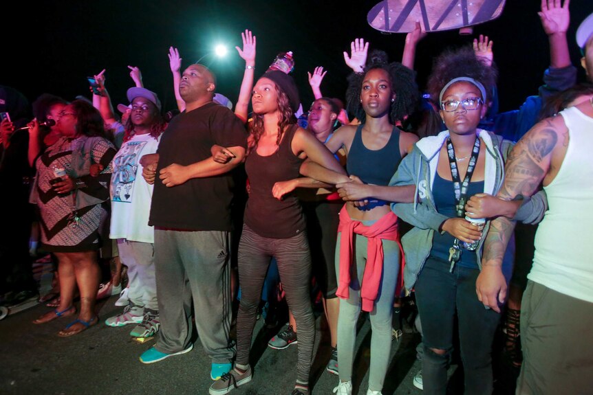 Protesters lock arms in front of a police line in El Cajon, a suburb of San Diego, California on September 28, 2016.