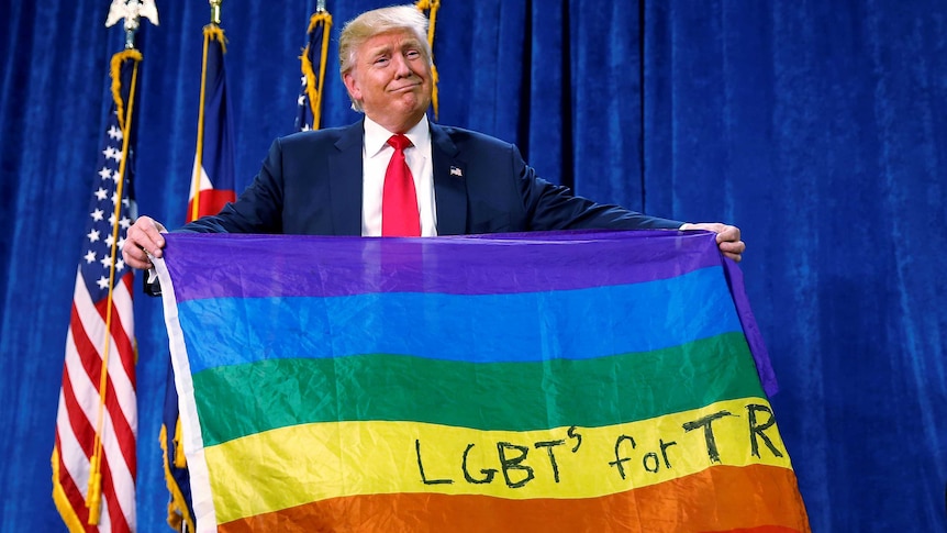 Donald Trump holds up a rainbow flag with LGBTs for TRUMP written on it.