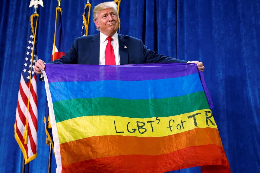 Donald Trump holds up a rainbow flag with LGBTs for TRUMP written on it.