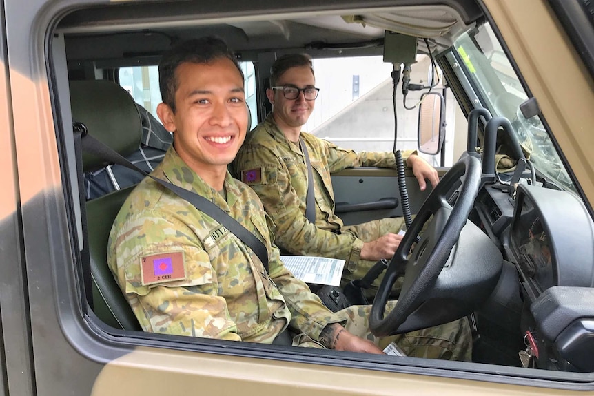 Two soldiers smiling inside an Army transport