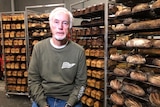 man in front of racks of bread in a bakery setting