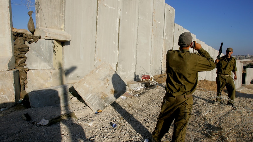 An Israeli soldier poses for souvenir photos along Israel's protective barrier.