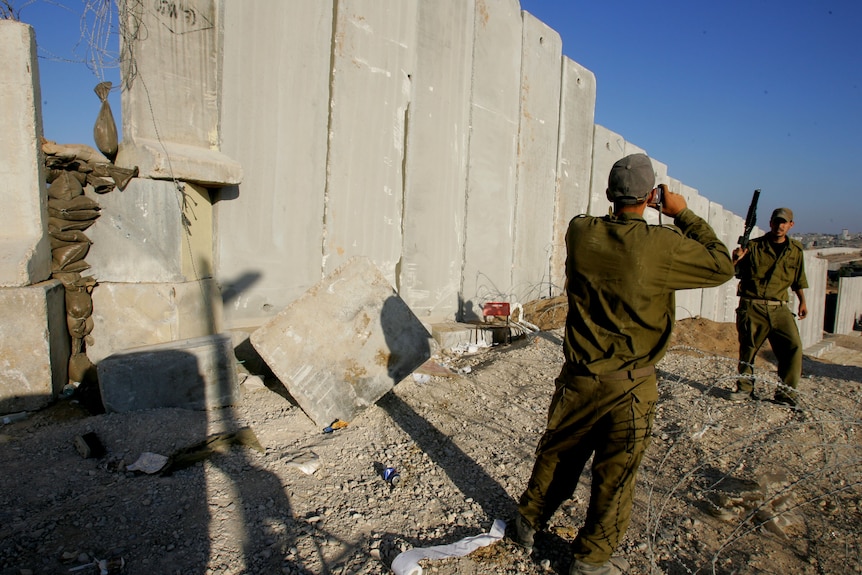 An Israeli soldier poses for souvenir photos along Israel's protective barrier.