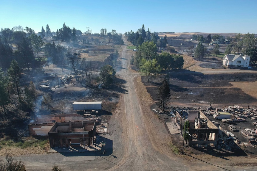 Houses on either side of a dirt road lay burned and in ruins.