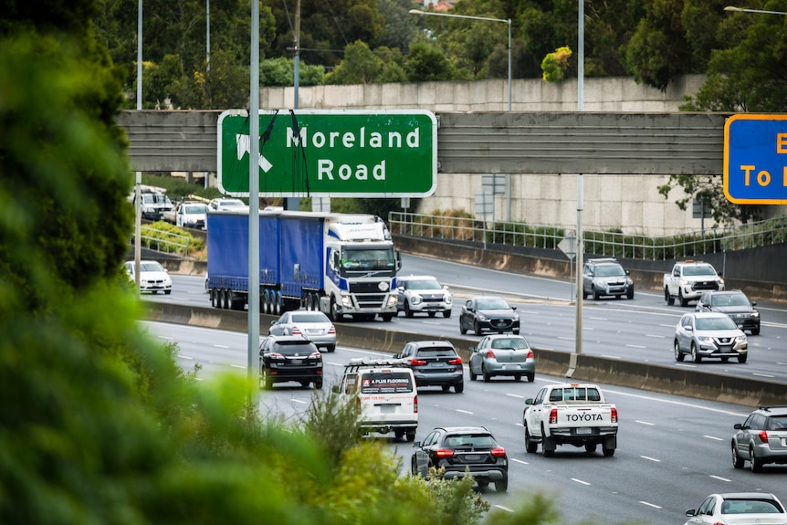 Traffic on a freeway with a sign to the Moreland Road exit overhead.