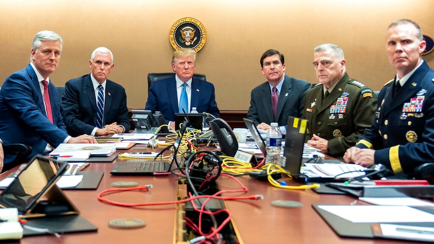 Donald Trump andy five senior military and political advisers sit around a table and look forward.