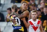A Richmond player smiles in triumph as he hangs in the arms of a teammate after a goal in a big game.