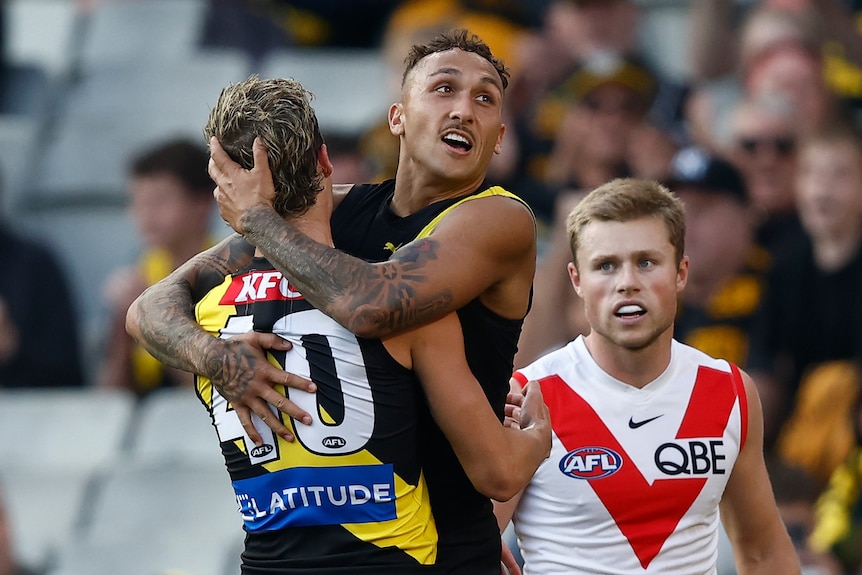 A Richmond player smiles in triumph as he hangs in the arms of a teammate after a goal in a big game.