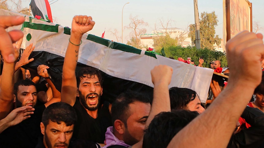 Mourners chant anti government slogans while carrying the Iraqi flag-draped coffin