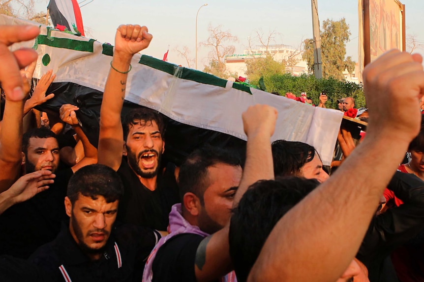 Mourners chant anti government slogans while carrying the Iraqi flag-draped coffin